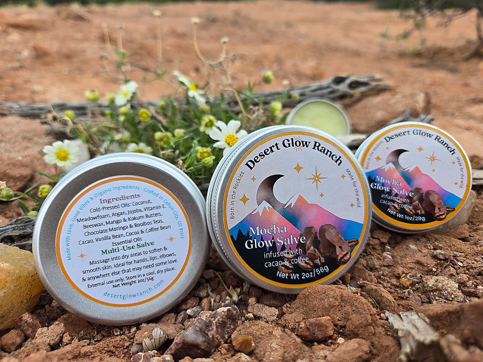 Mocha glow salve organic coffee and chocolate moisturizer tins on desert ground with natural plants