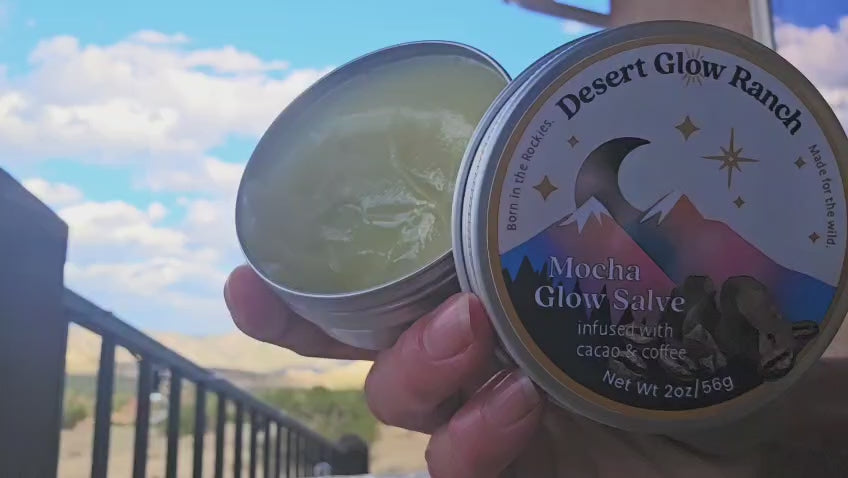 Mocha glow salve organic coffee and chocolate moisturizer being applied on skin outdoors with mountain background